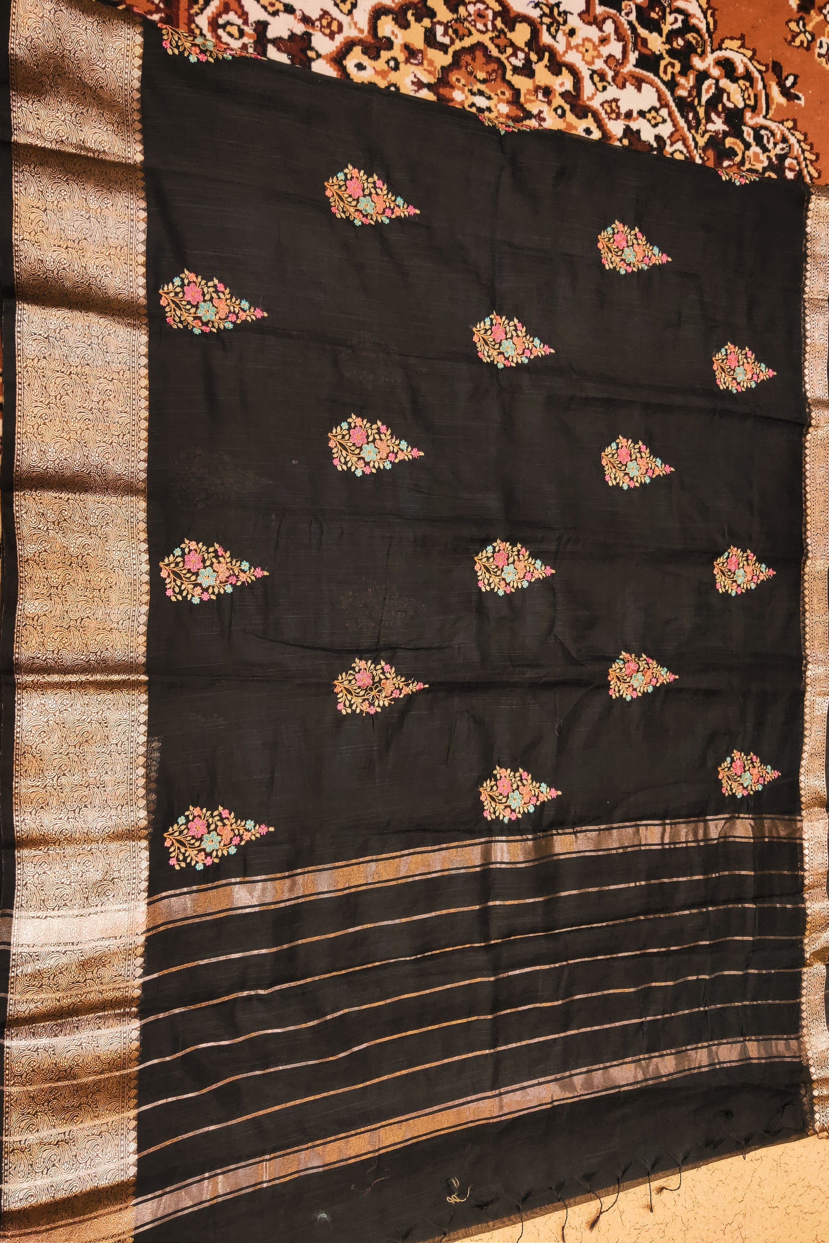 Black saree with floral patterns on a textured surface