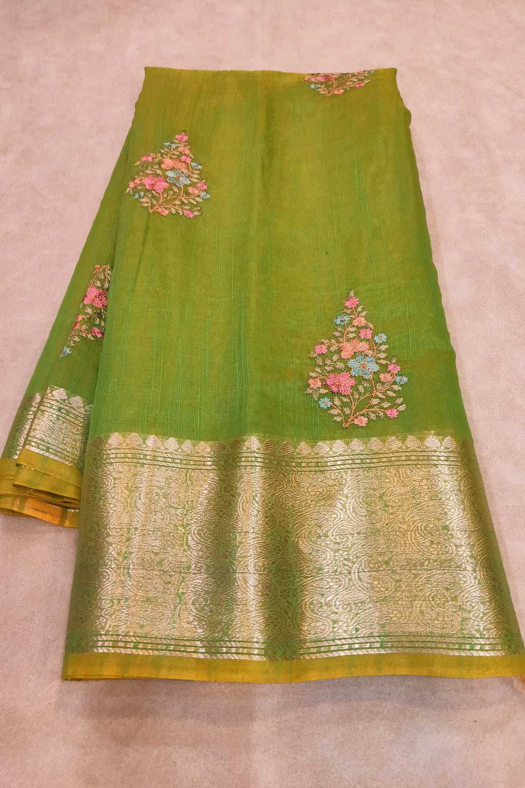 Green saree with floral patterns on a beige background