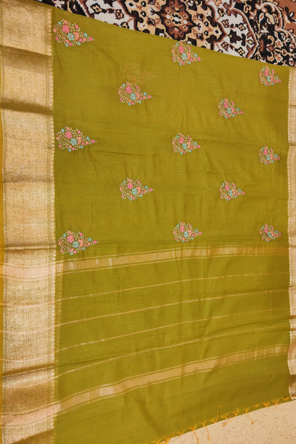 Green saree with floral patterns on a patterned fabric background