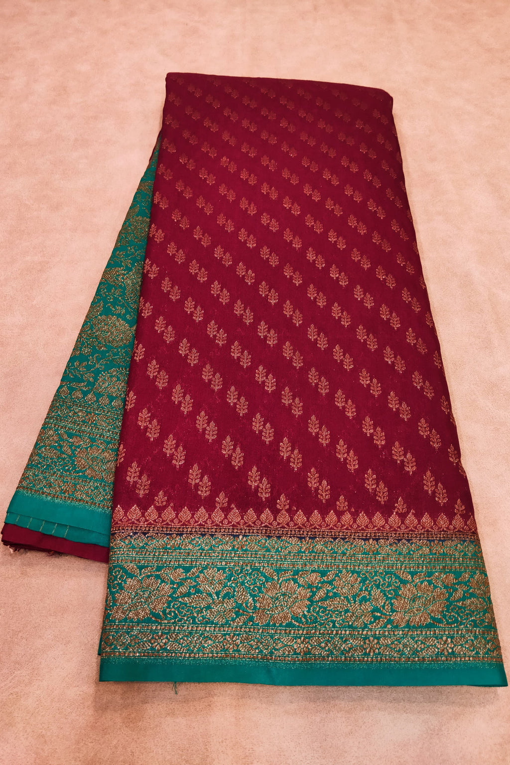 Maroon and green saree with floral patterns on a beige background