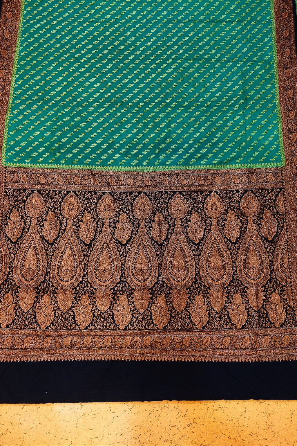 Green and brown patterned fabric on a textured surface