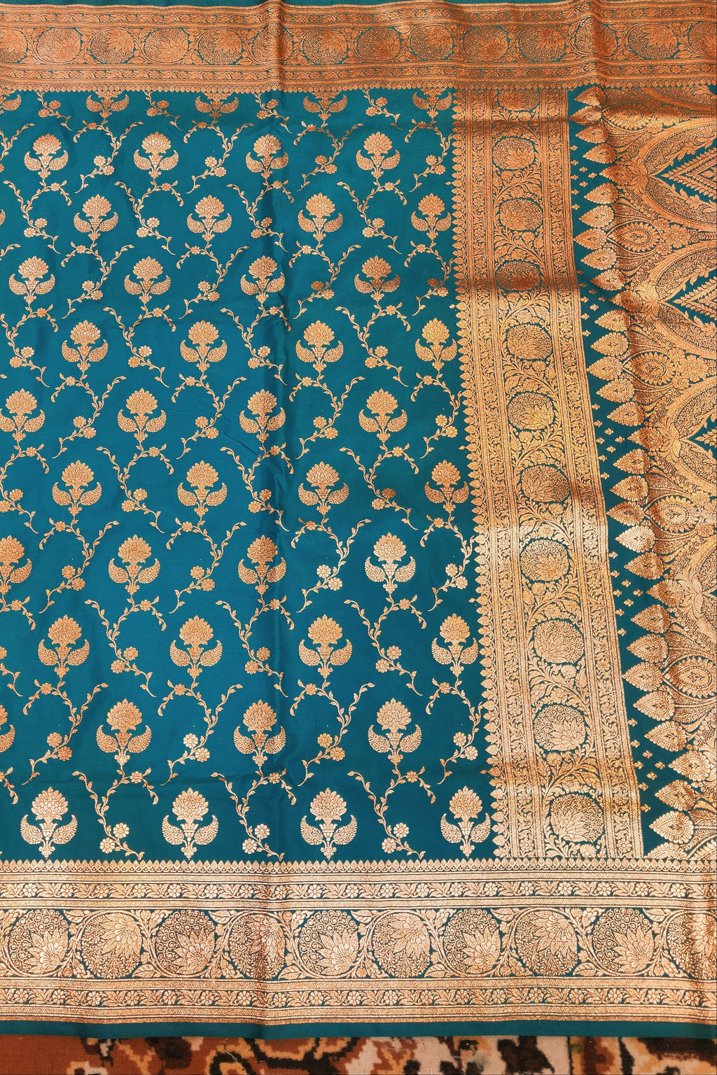 Teal fabric with gold floral patterns on a textured background