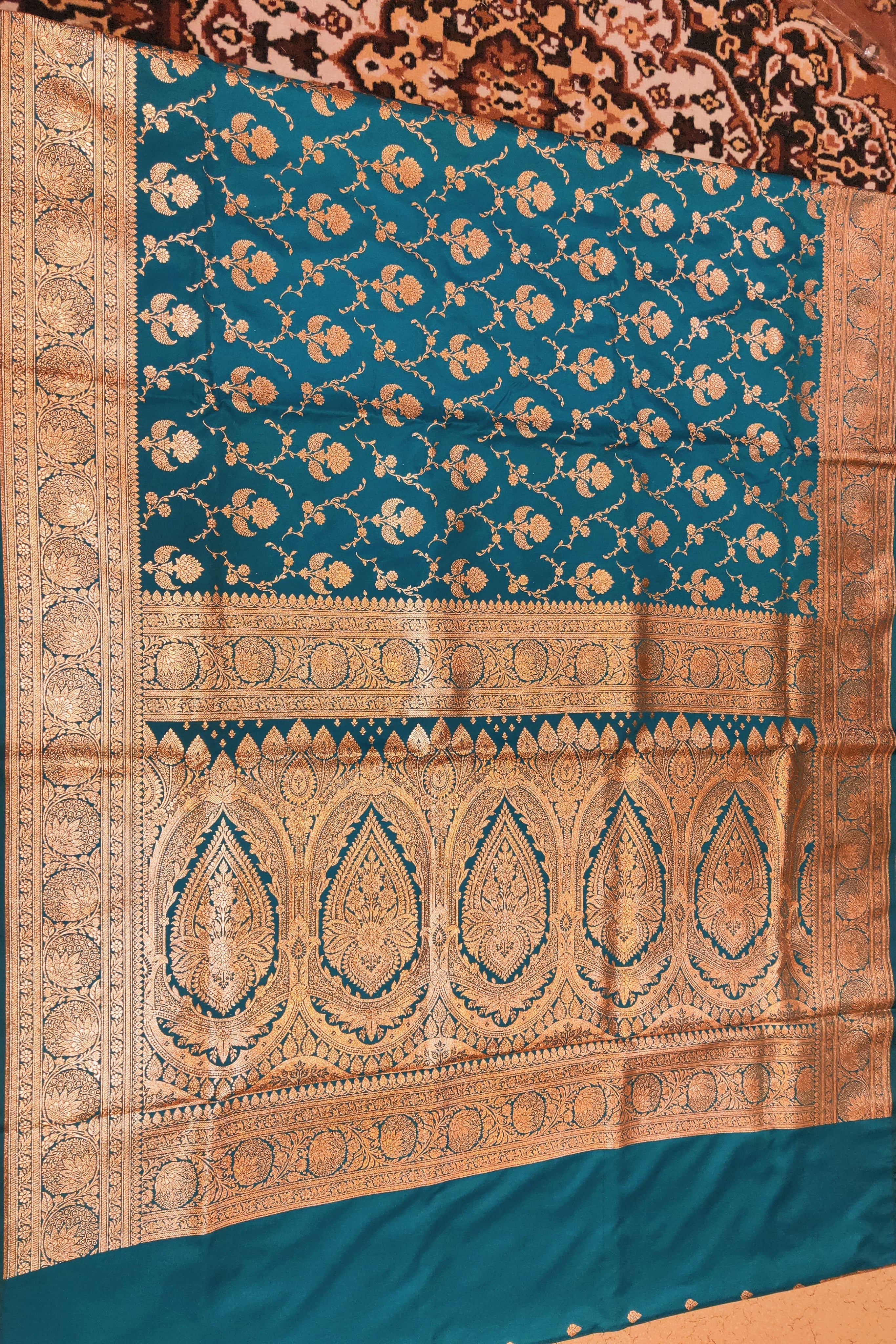 Teal and gold patterned fabric on a wooden surface