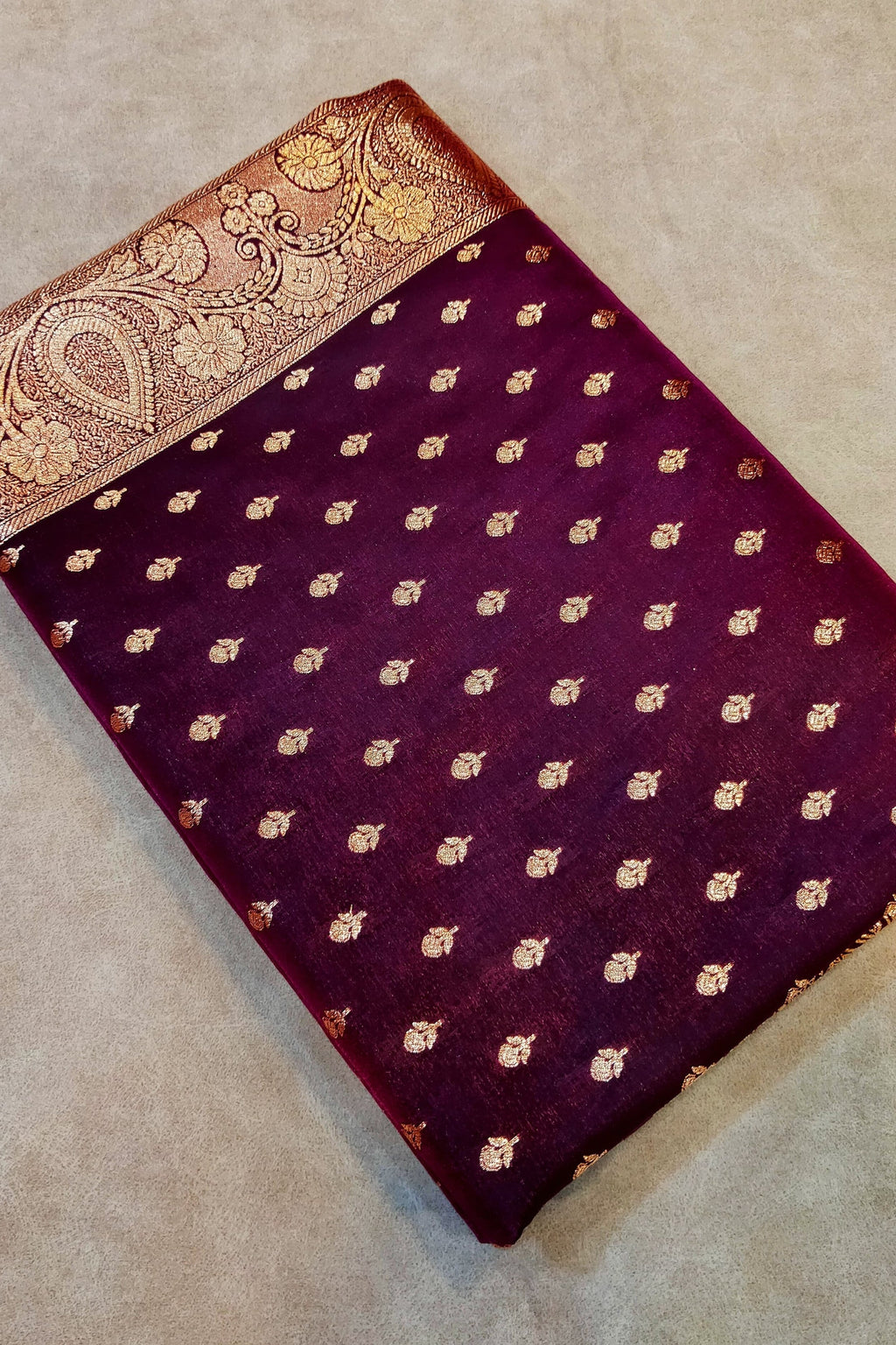 Purple fabric with gold patterns on a beige surface