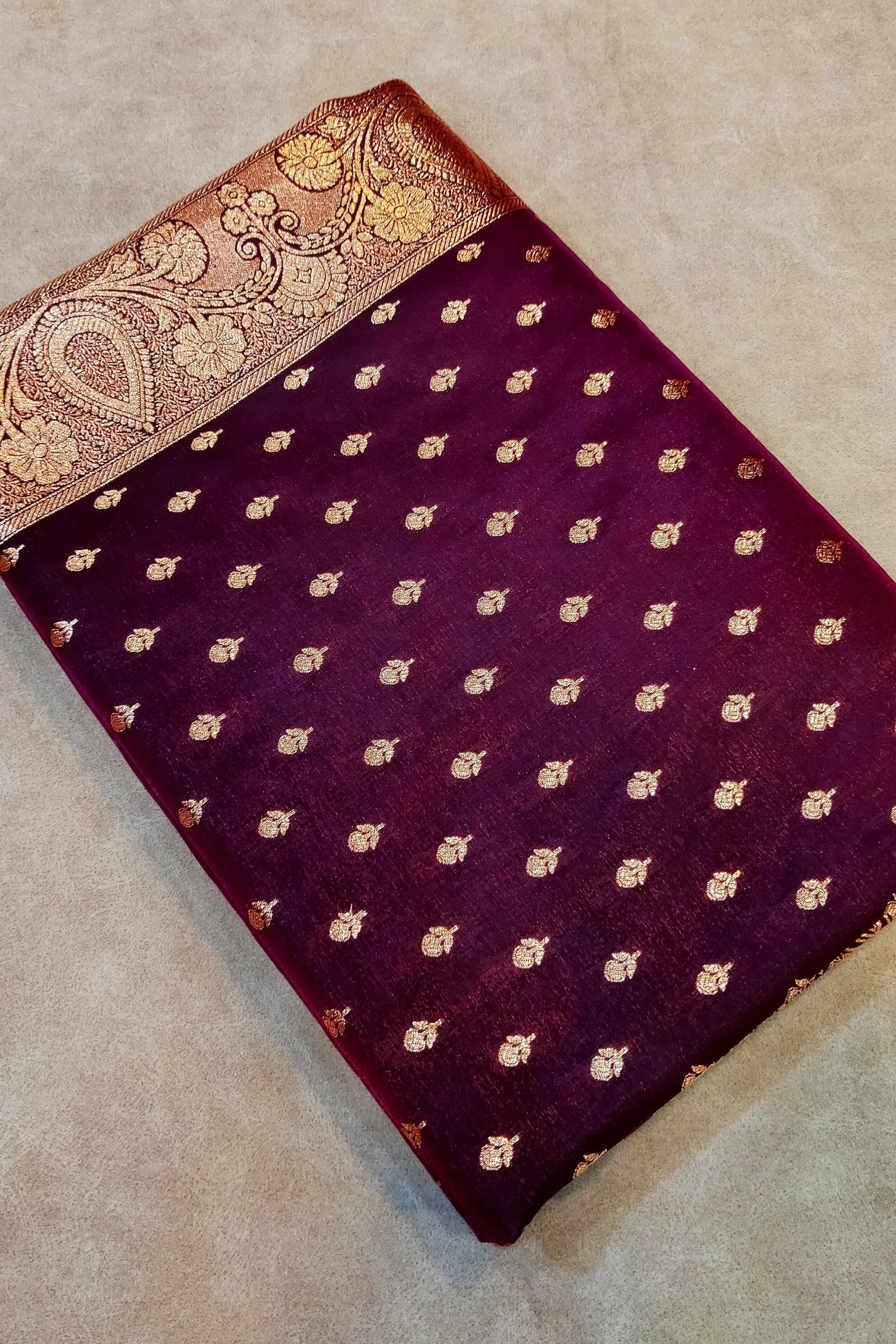 Purple fabric with gold patterns on a beige surface