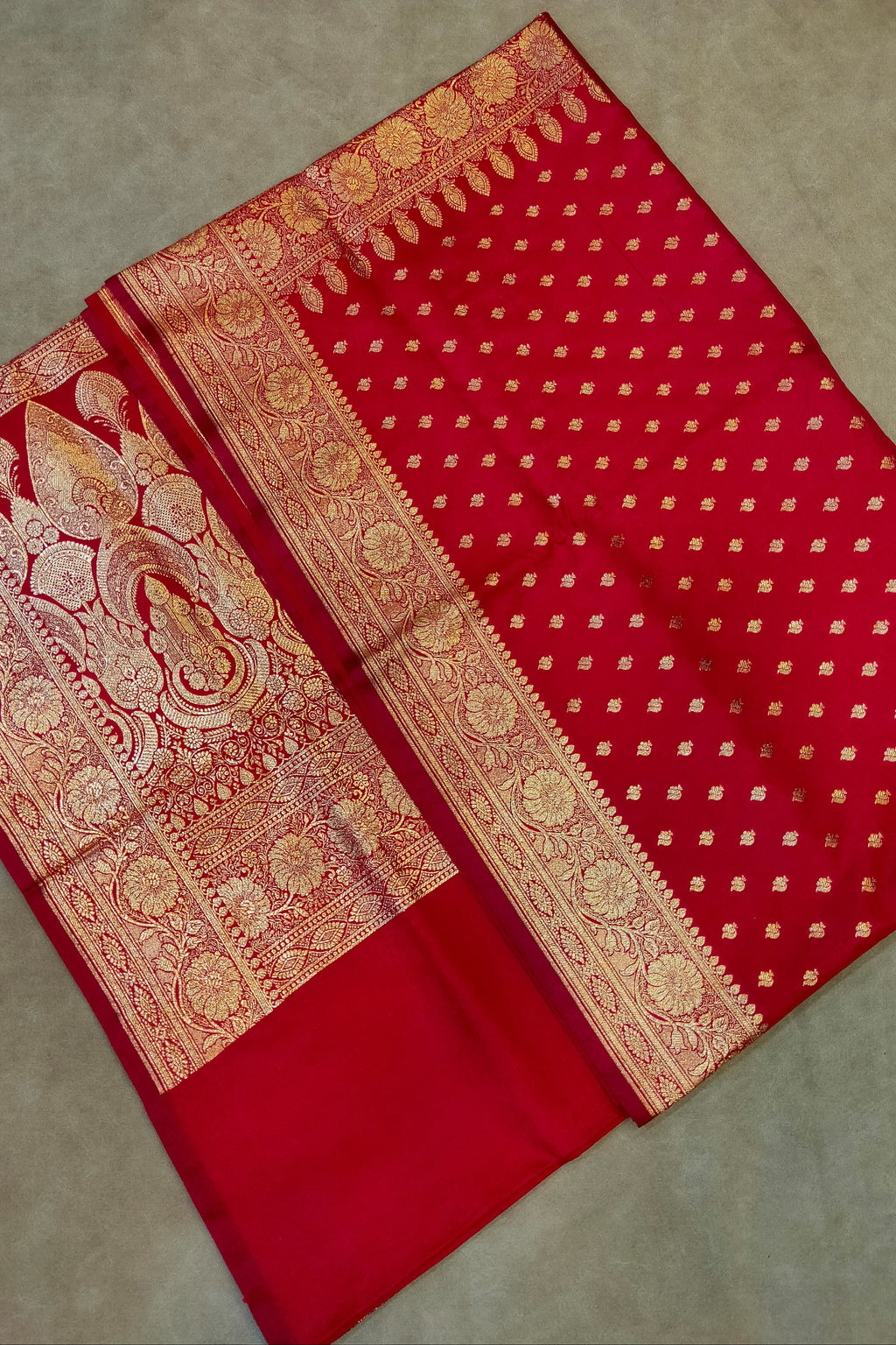 Red saree with gold patterns on a neutral background
