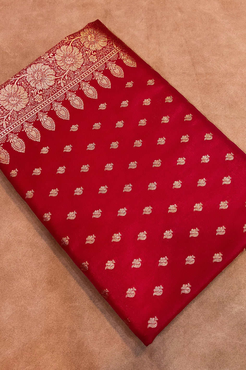 Red fabric with gold patterns on a brown background