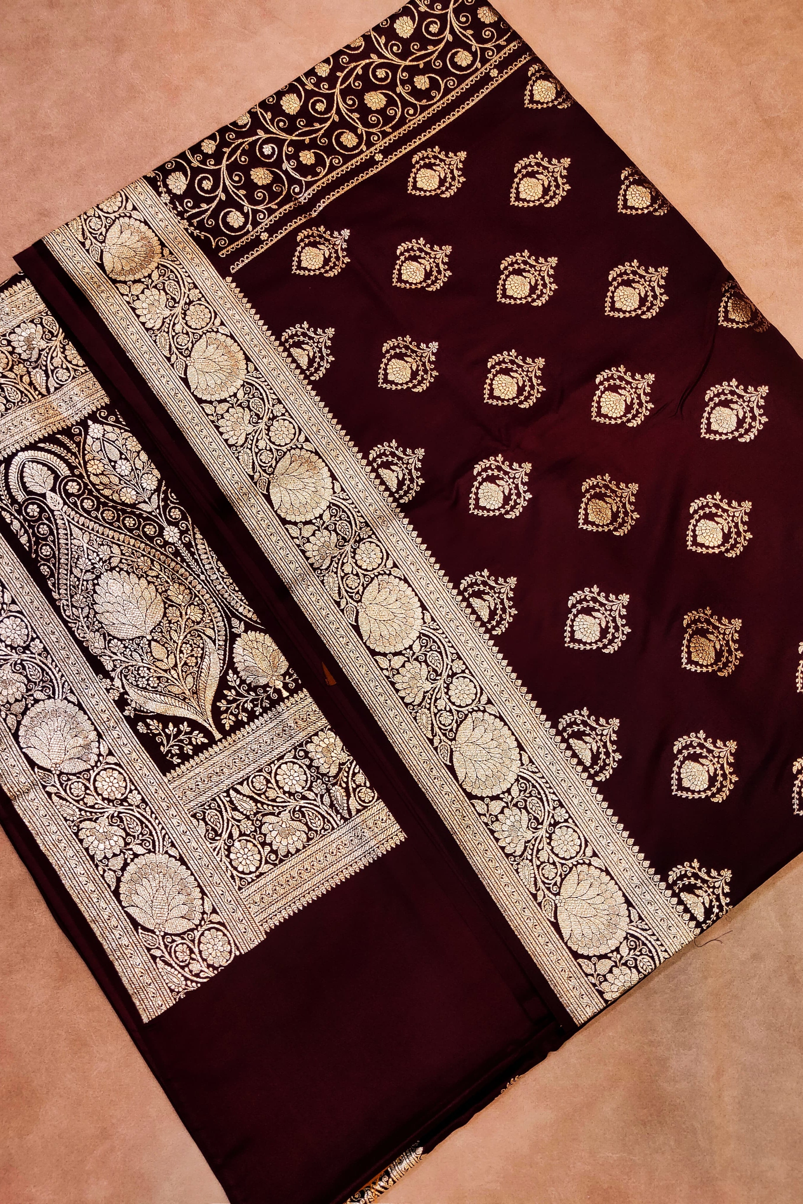 Maroon saree with gold embroidery on a beige background