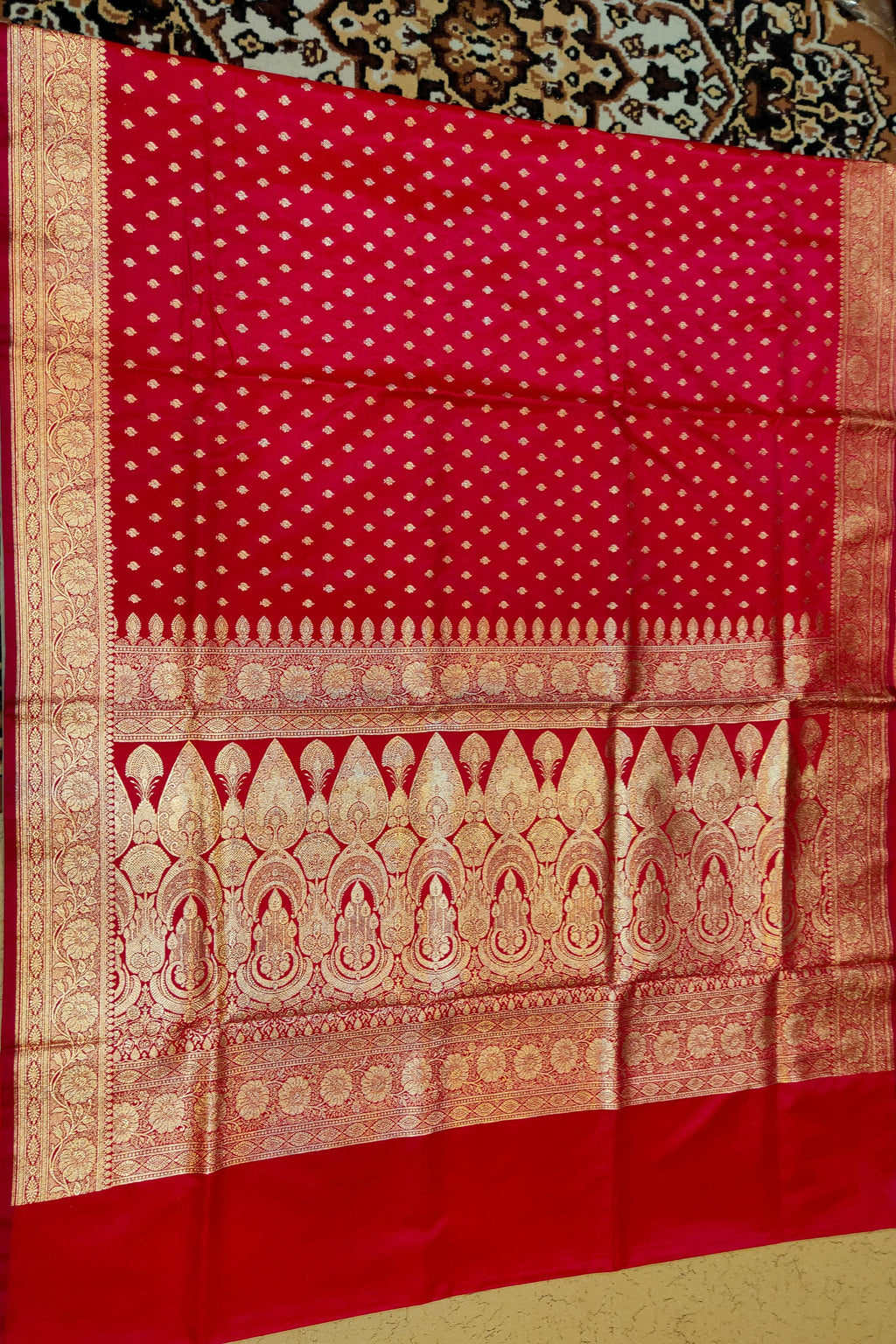 Red fabric with gold patterns on a patterned surface