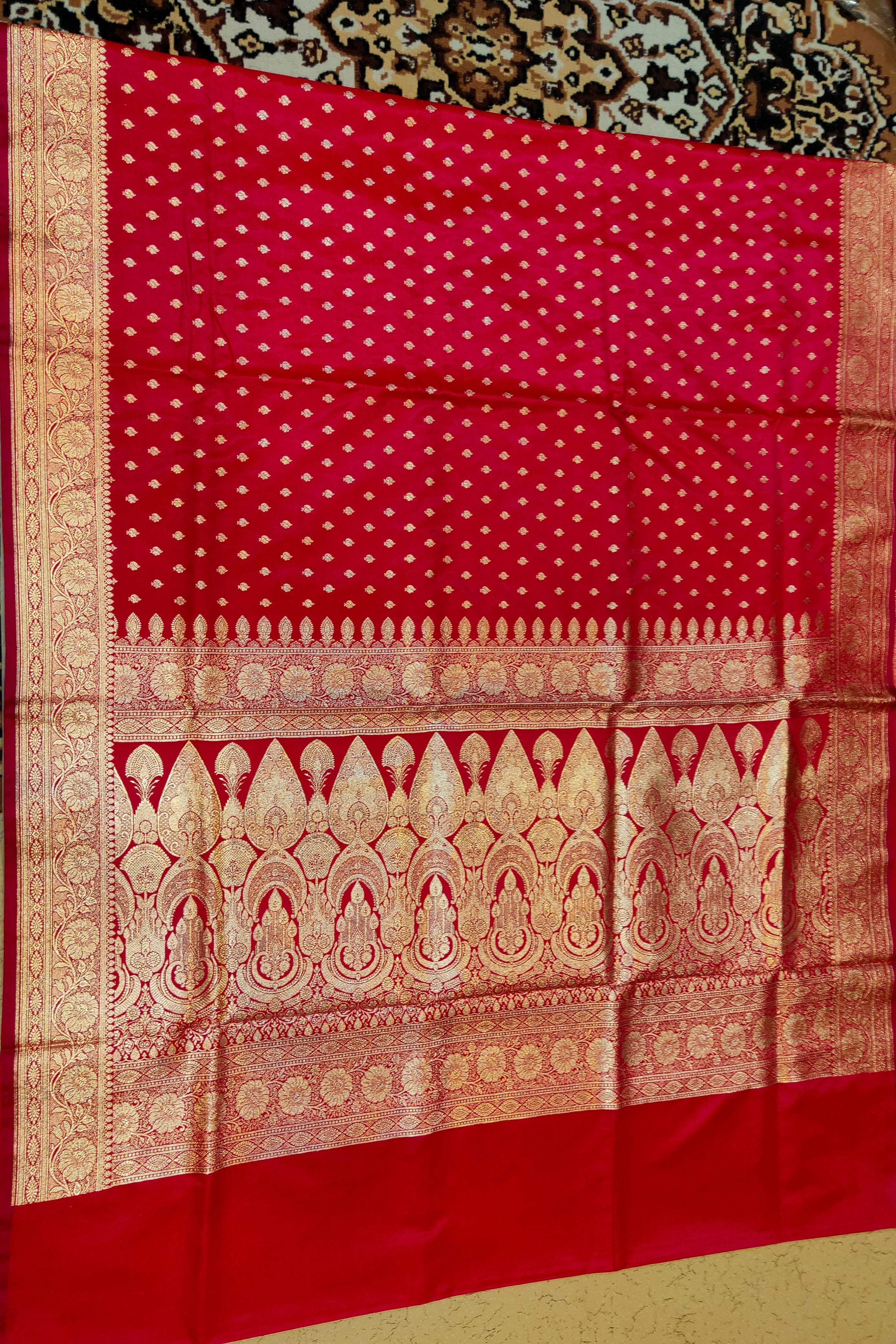 Red fabric with gold patterns on a patterned surface