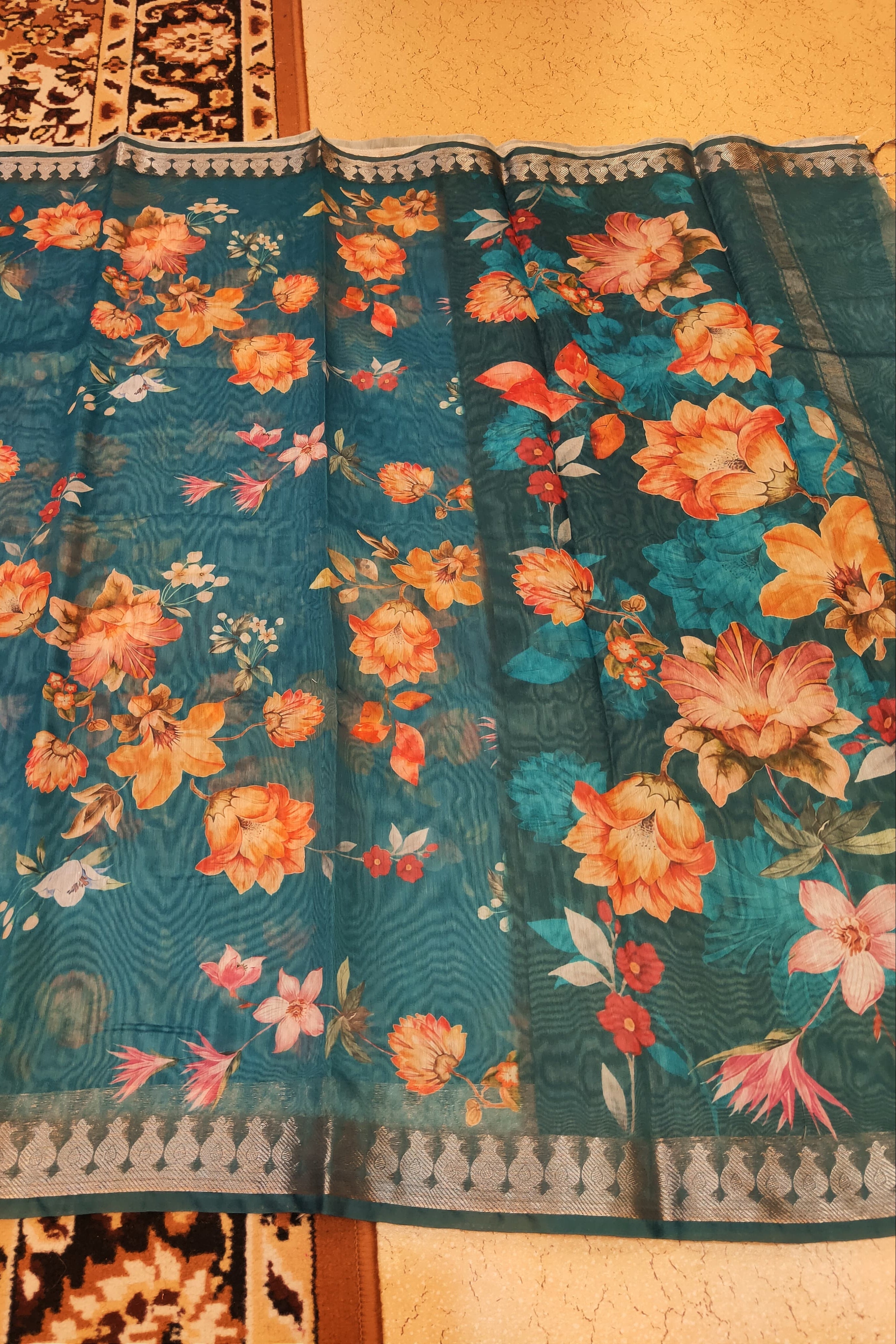 Floral patterned fabric with orange and pink flowers on a teal background.