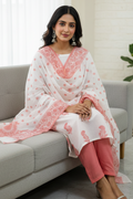 Woman in a white and pink traditional outfit sitting on a couch in a bright room.