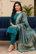 Woman in teal traditional outfit with a patterned dupatta sitting on a blue couch.