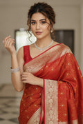 Woman wearing a red saree with gold patterns indoors