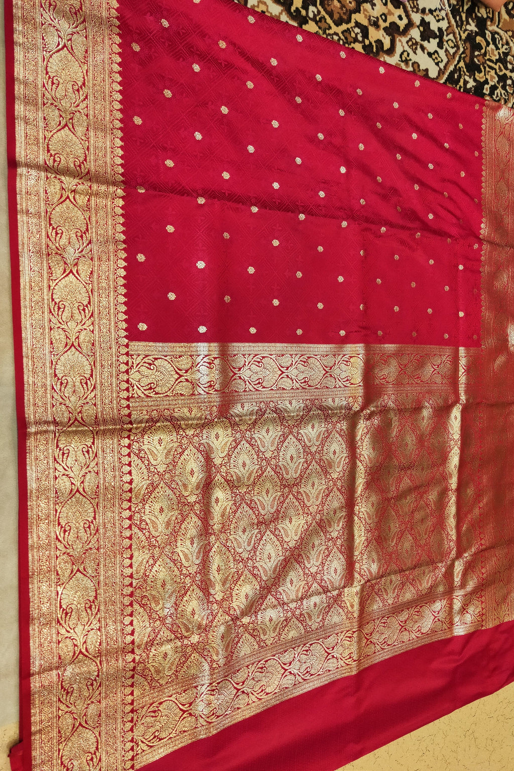 Red saree with gold patterns on a plain background