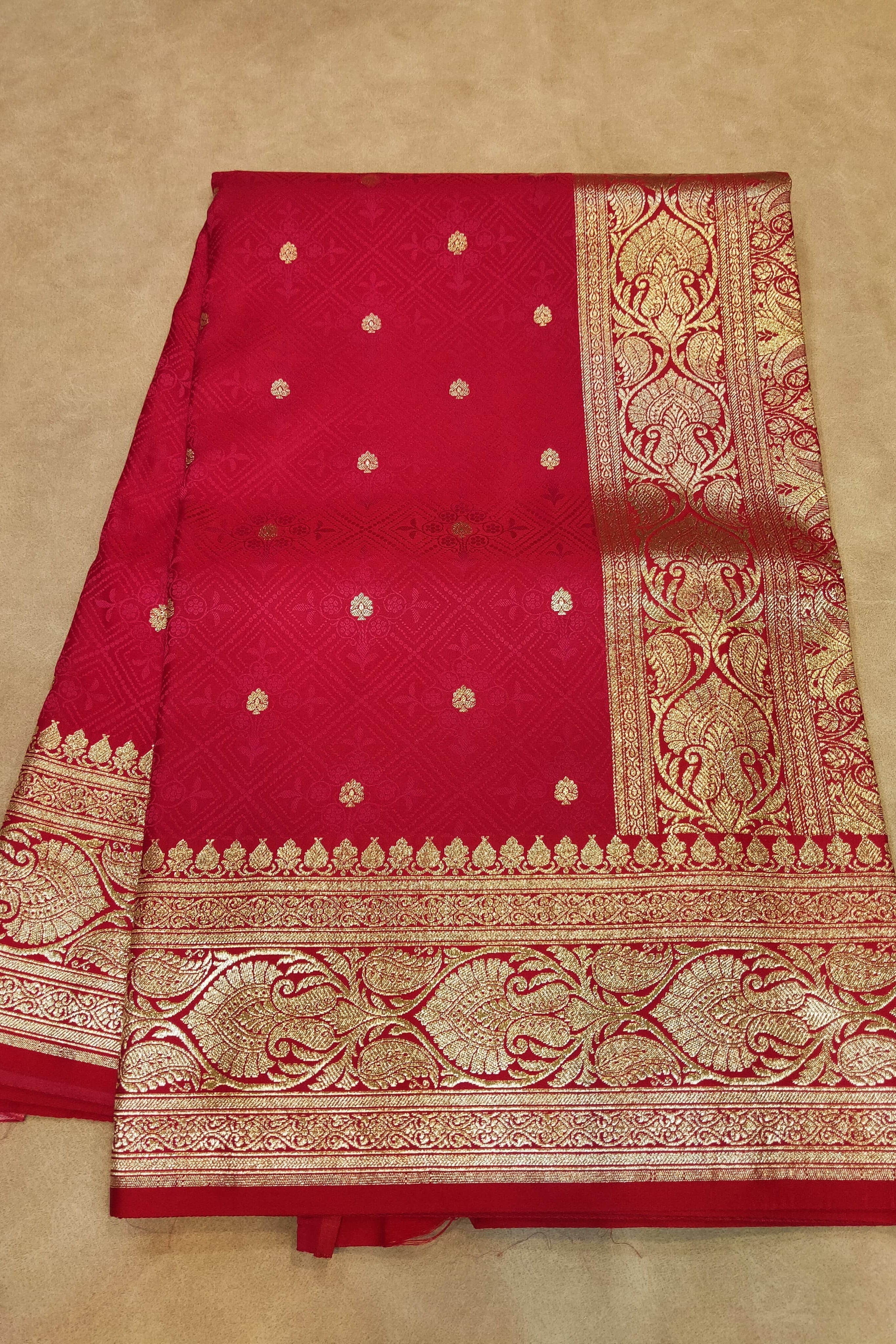 Red saree with gold patterns on a beige background
