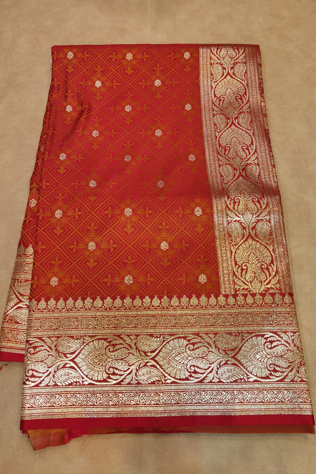 Red saree with gold patterns on a beige background