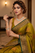 Woman wearing a green saree with intricate patterns indoors