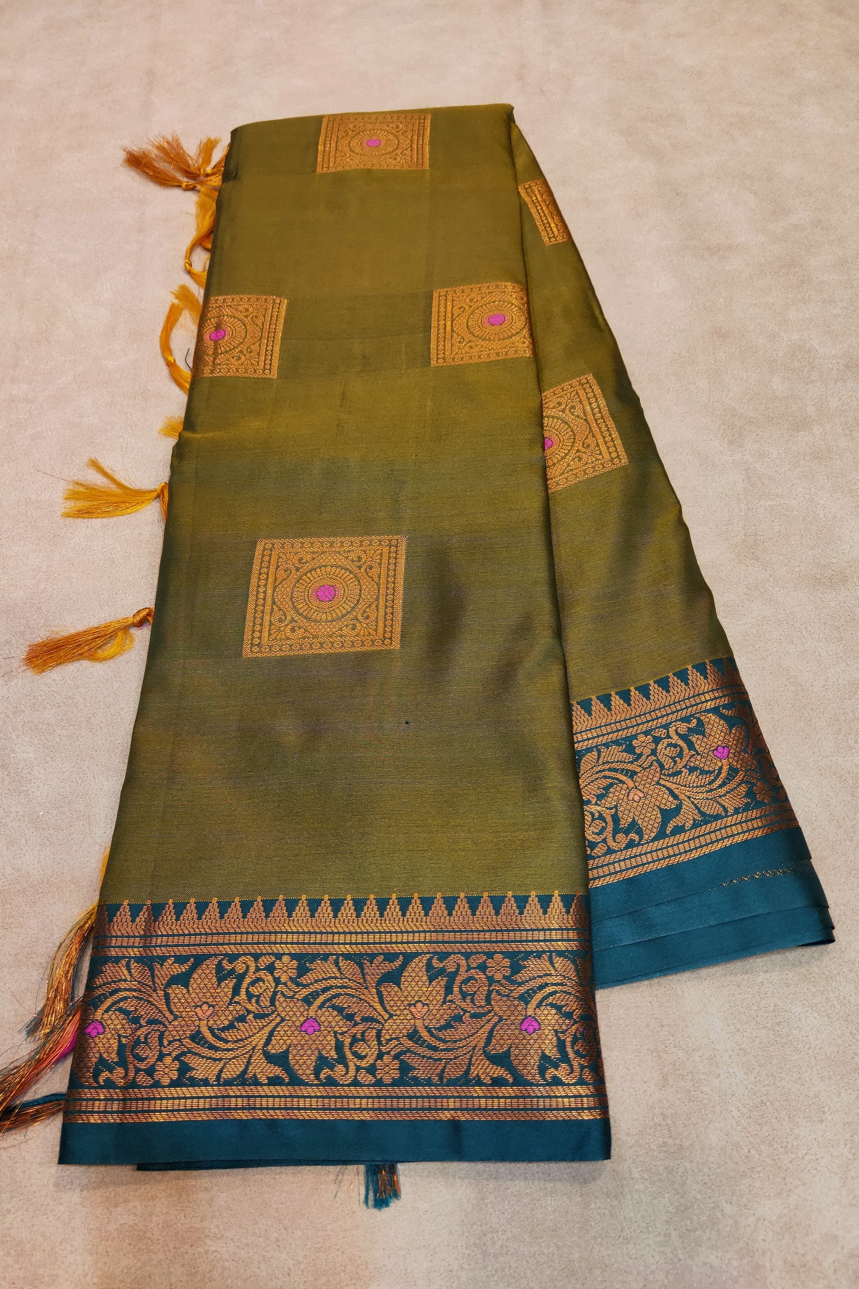 Green saree with gold and blue patterns on a beige background