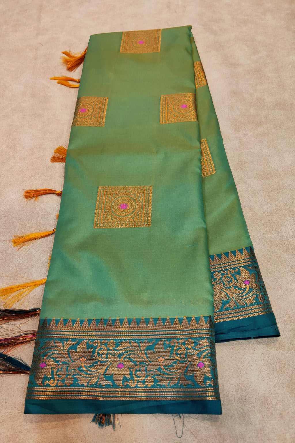 Green saree with gold and blue patterns on a beige background