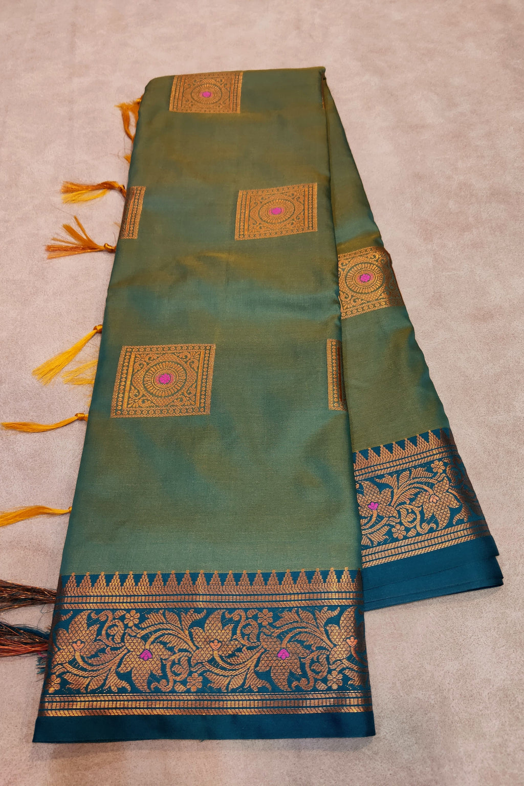 Green saree with gold and blue patterns on a beige background