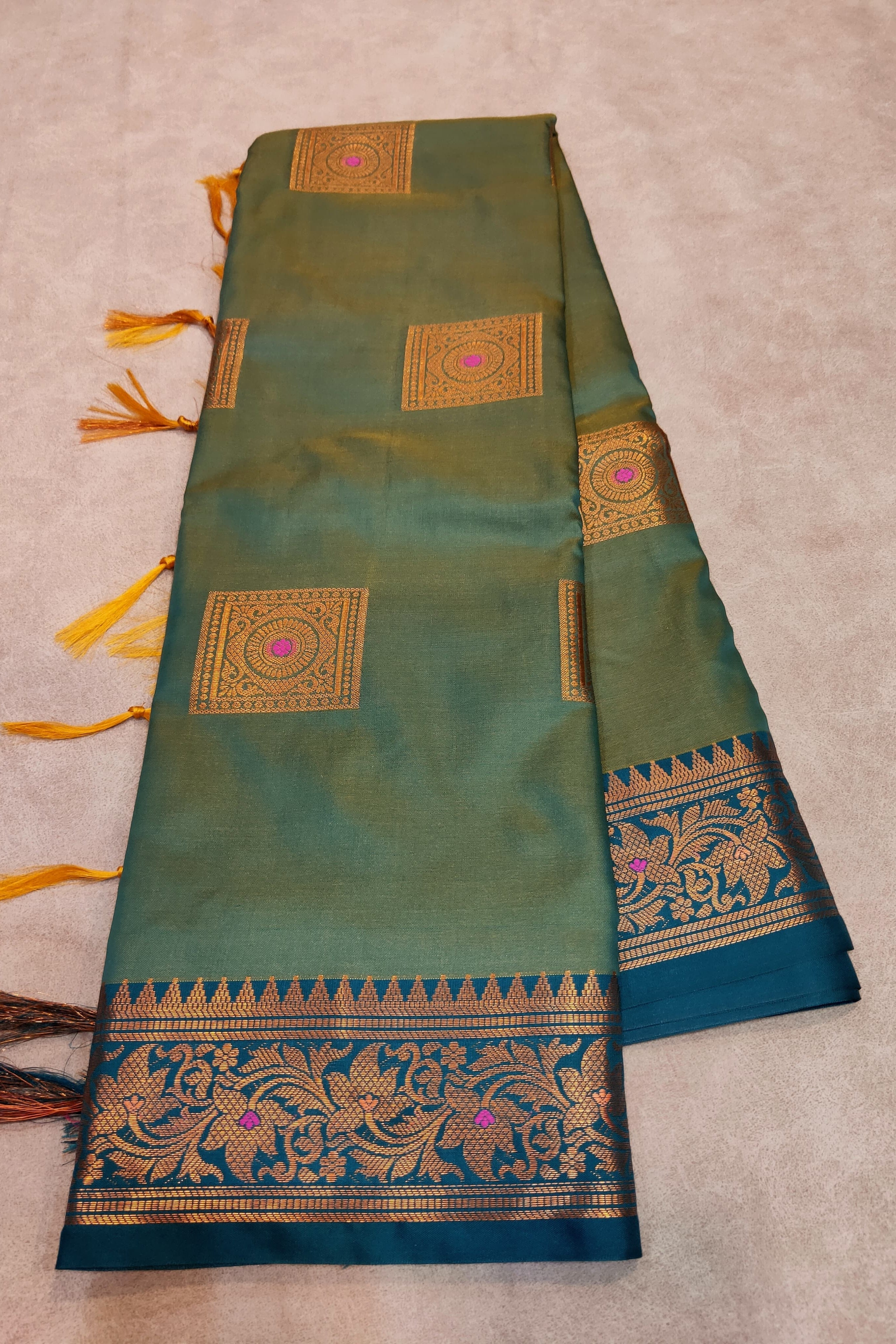 Green saree with gold and blue patterns on a beige background