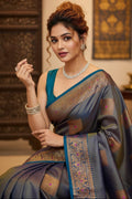 Woman in a traditional saree with intricate patterns, posing indoors.