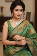 Woman in a green saree with gold border indoors