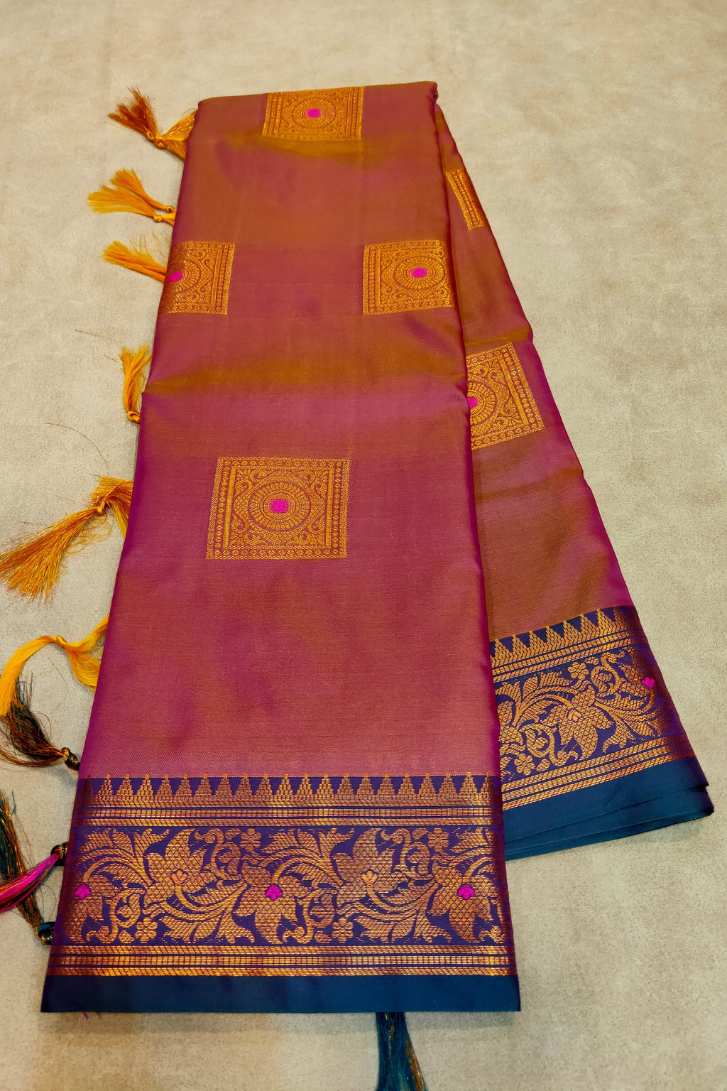 Woman wearing a green saree with intricate patterns indoors.