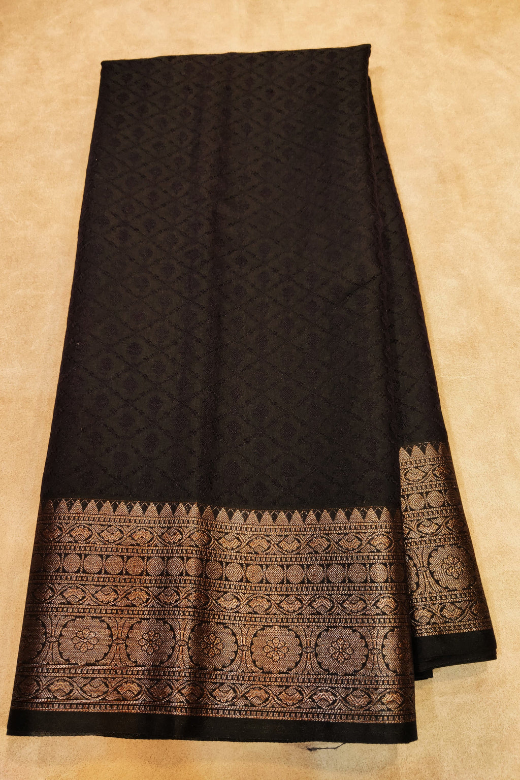 Black fabric with intricate patterns on a beige background