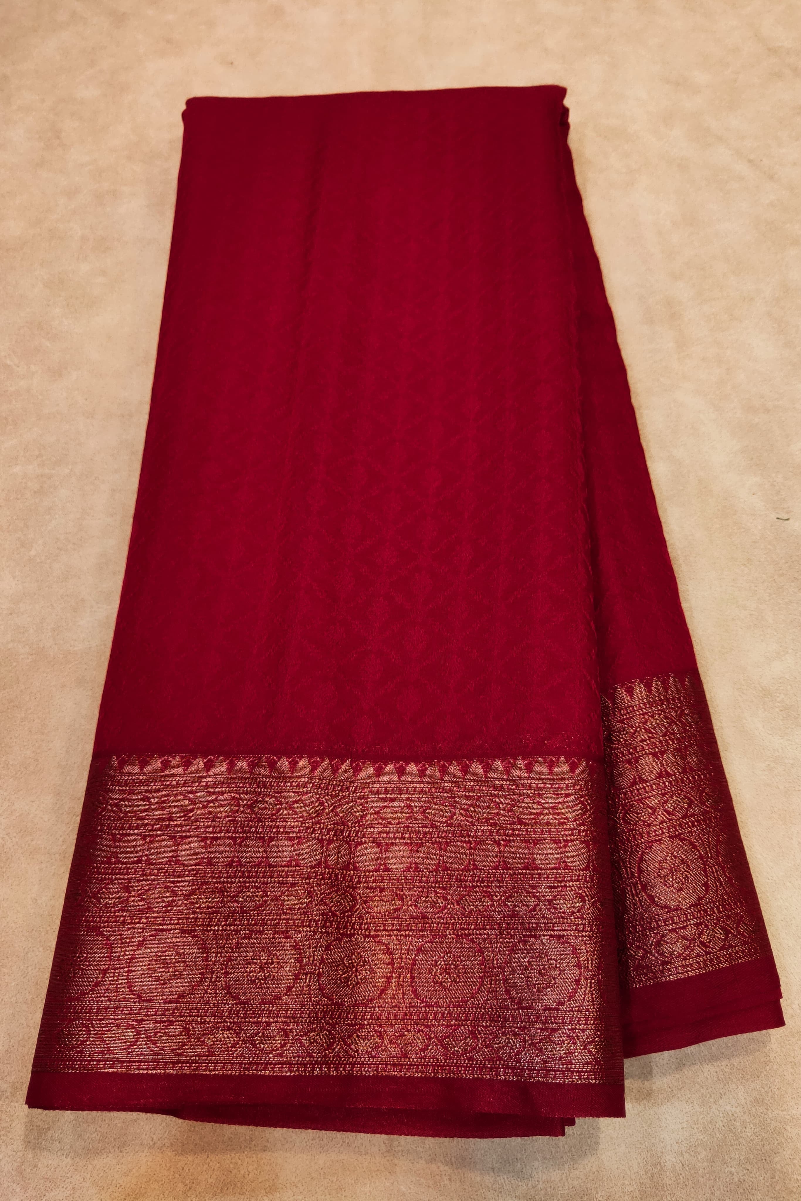 Red fabric with a patterned border on a beige background