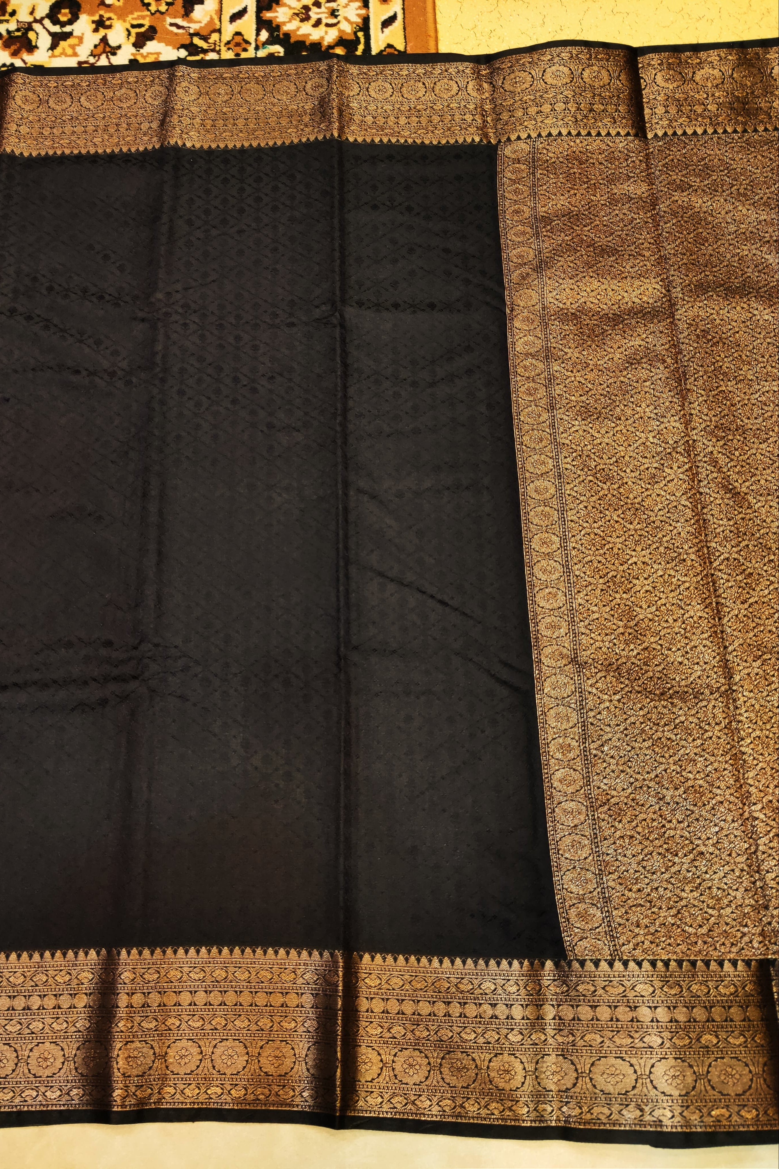 Black saree with gold border on a plain background