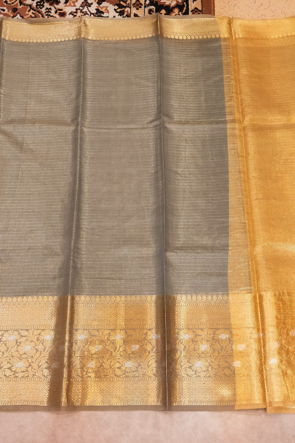 Sari with a gold and gray pattern on a plain background
