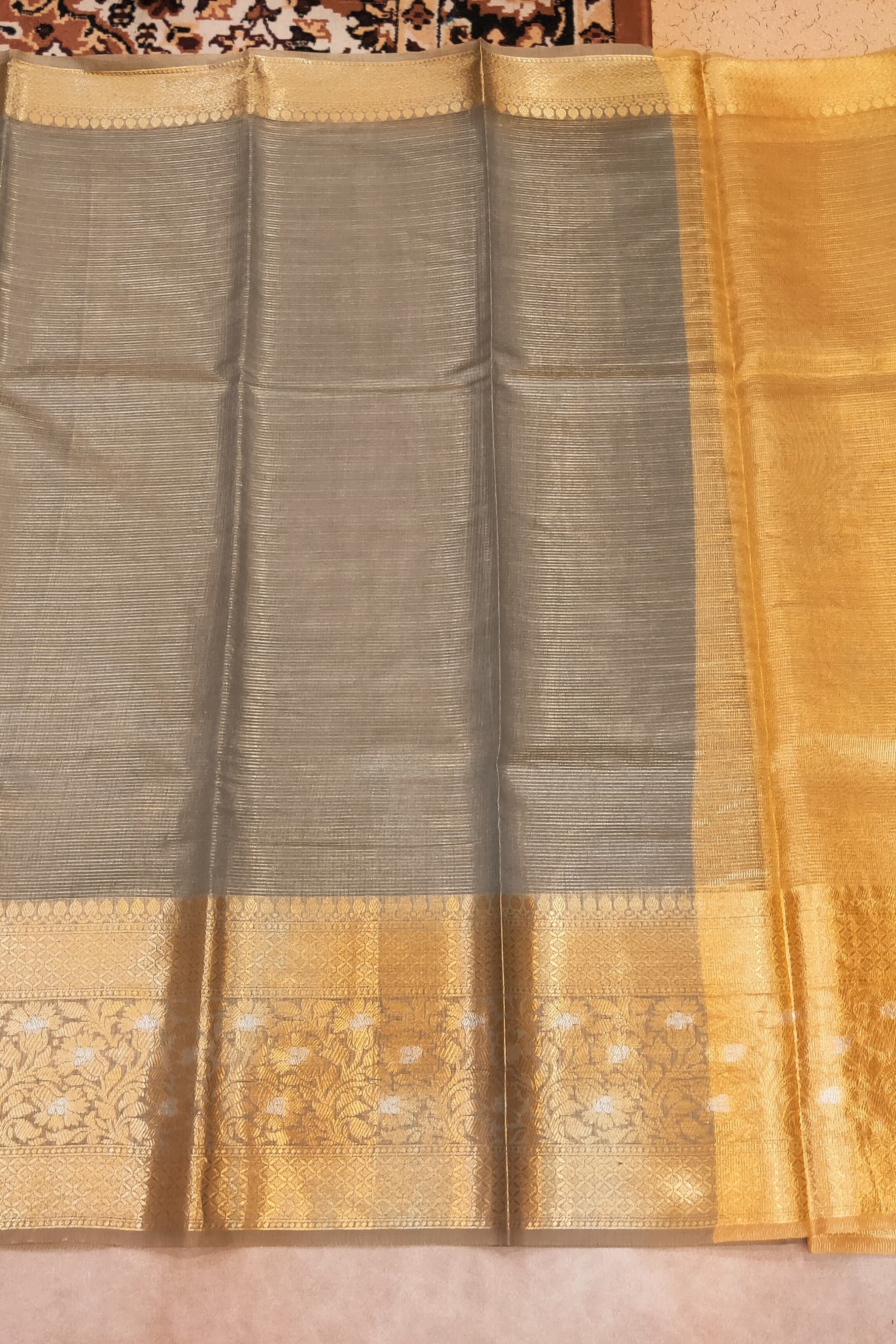 Sari with a gold and gray pattern on a plain background