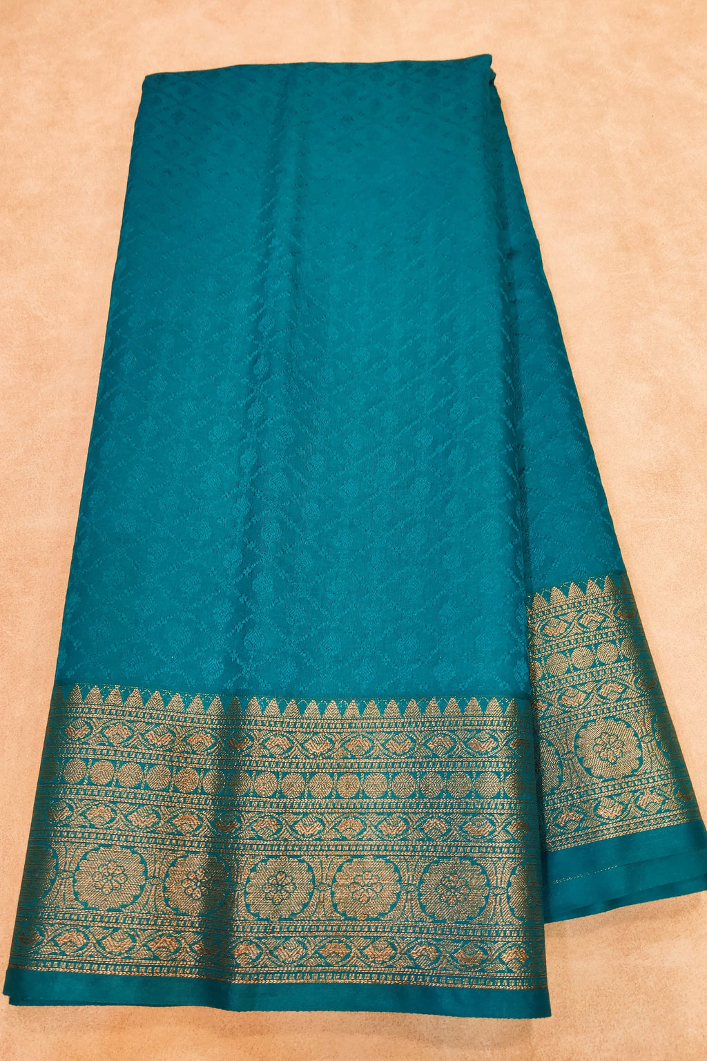 Teal fabric with decorative border on a beige background