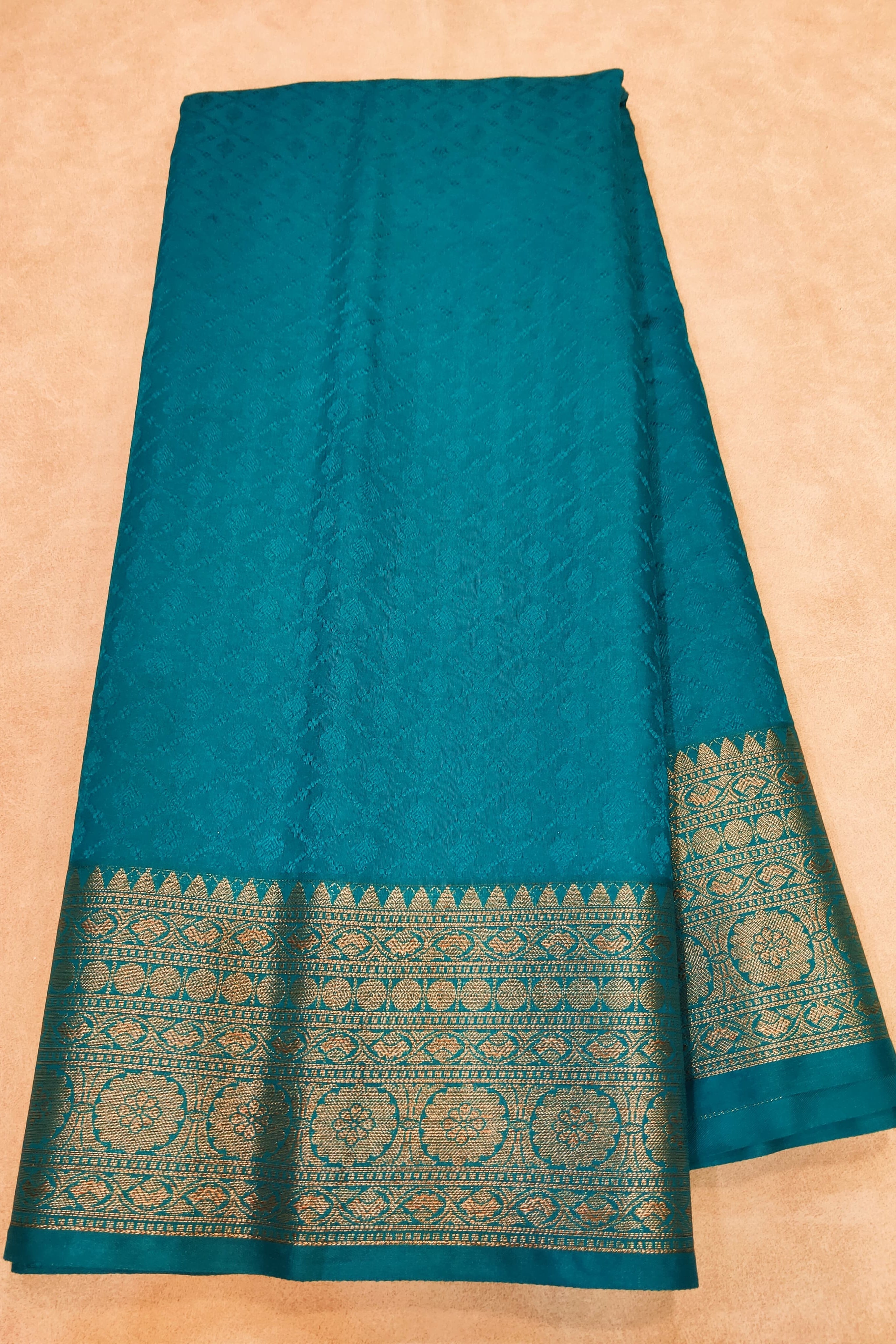 Teal fabric with decorative border on a beige background