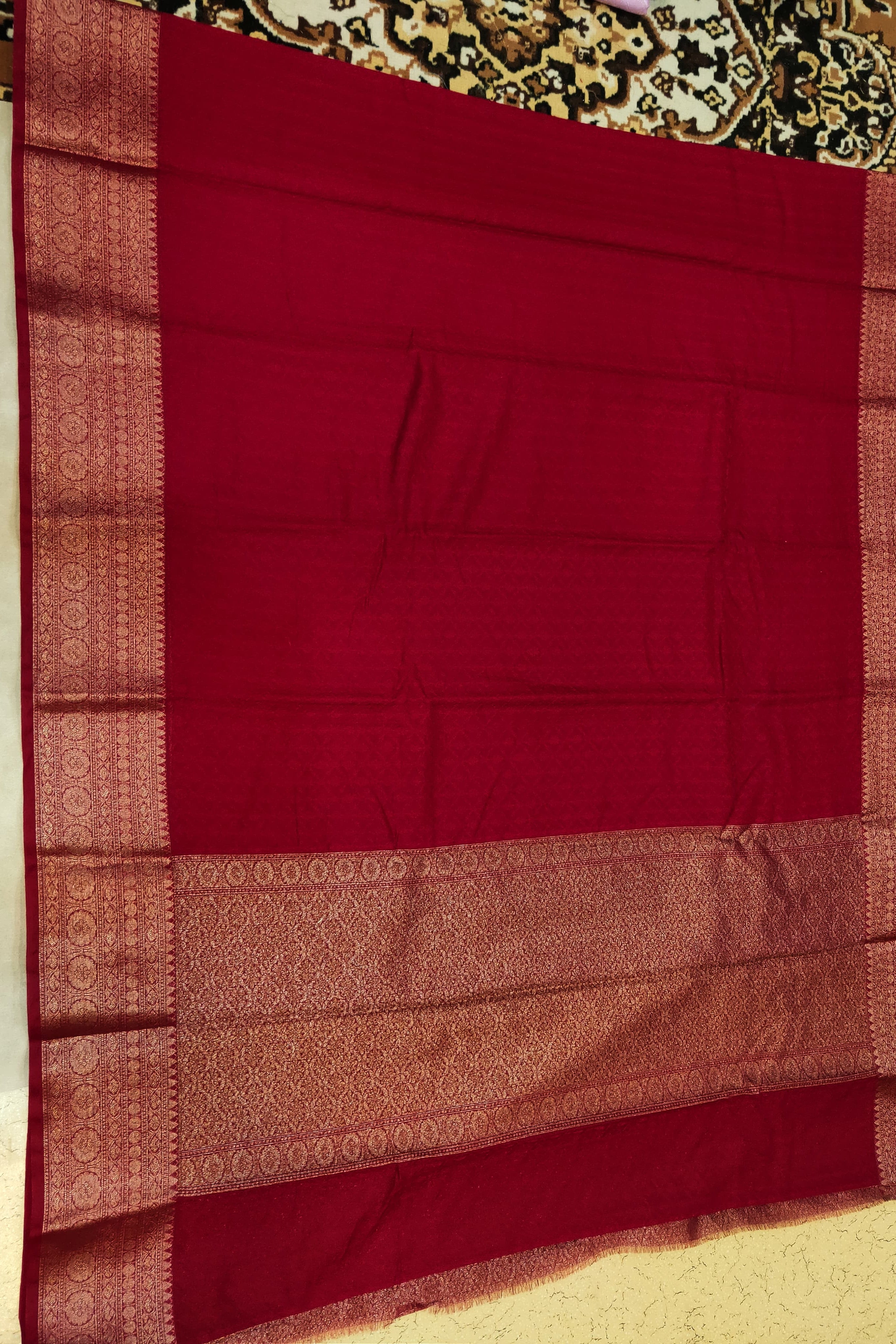 Red saree with a patterned border on a plain background