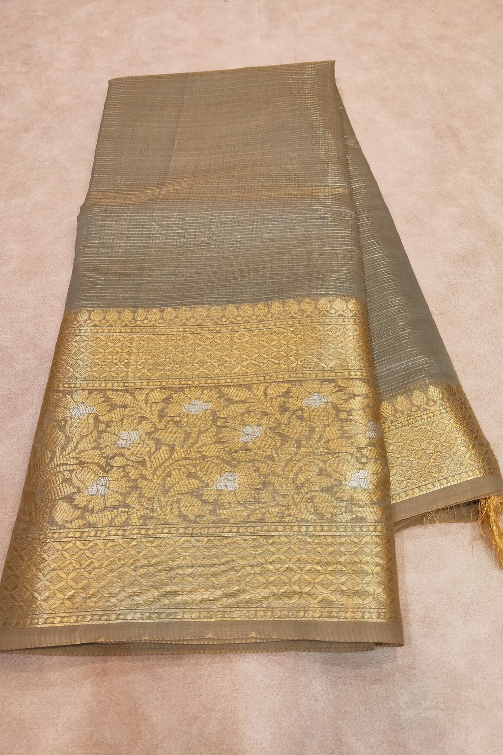 Traditional saree with gold and green pattern on a beige background