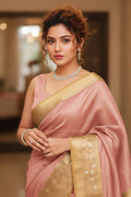 Woman in a pink and gold saree with jewelry indoors