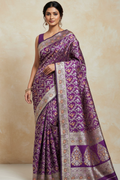 Woman wearing a purple saree with intricate patterns on a beige background