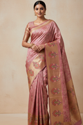 Woman wearing a pink and beige saree with a plain background