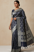 Woman wearing a navy blue and gray saree with a beige background
