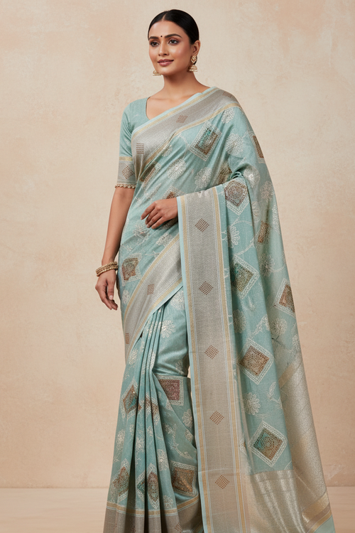 Woman wearing a light blue saree with a subtle pattern on a beige background