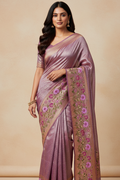 Woman wearing a pink saree with floral patterns on a beige background