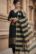 Woman in traditional attire with a striped dupatta against a beige wall.