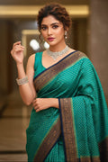 Woman in a green saree with gold border indoors