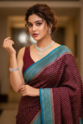 Woman wearing a maroon saree with blue border indoors