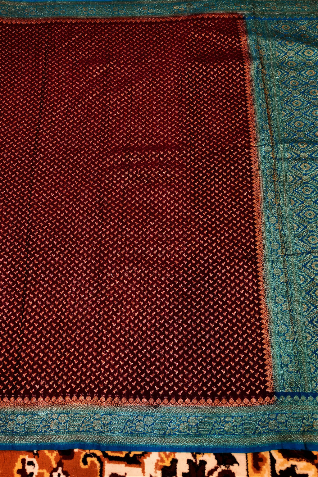 Maroon fabric with blue border on a patterned background