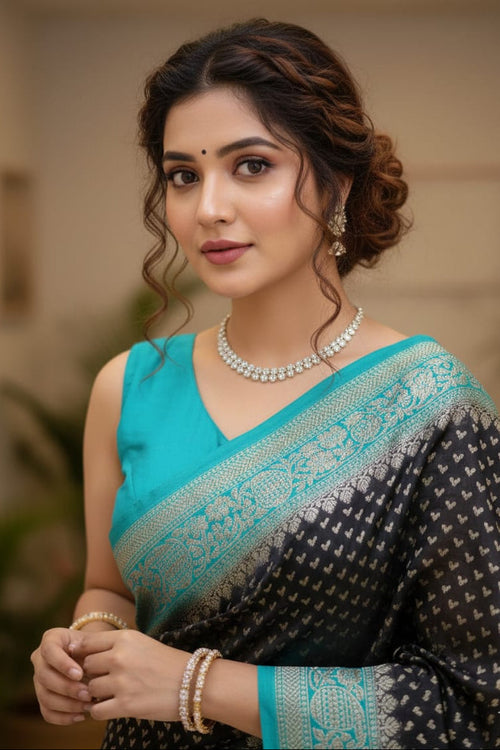 Woman wearing a black and blue saree with jewelry indoors