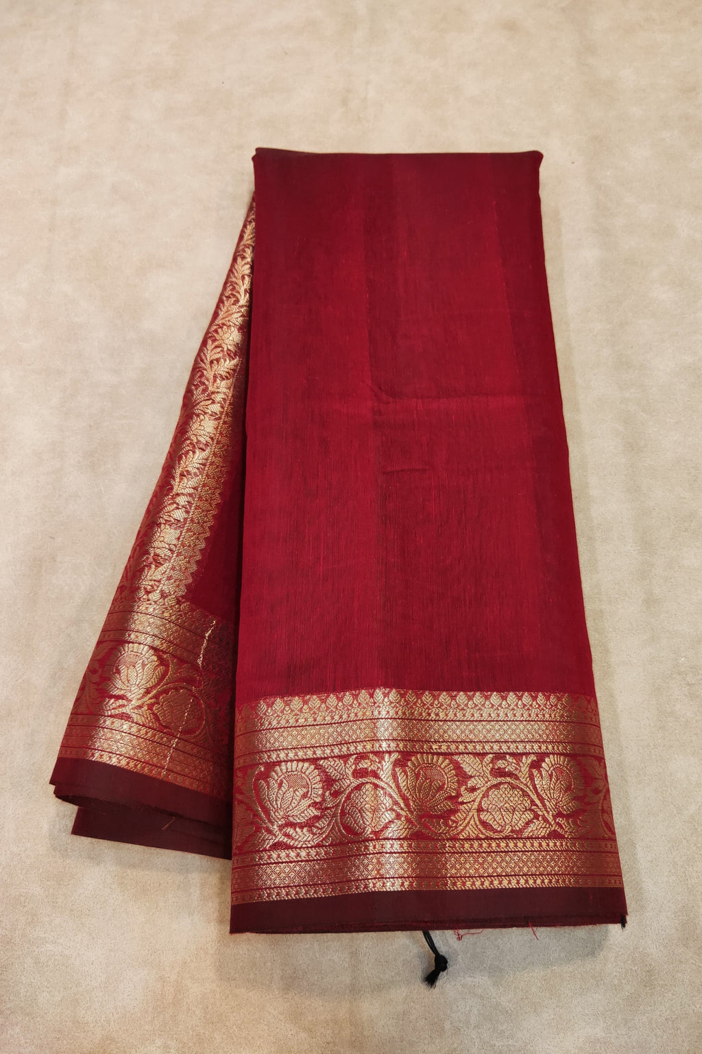 Red saree with gold border on a beige background